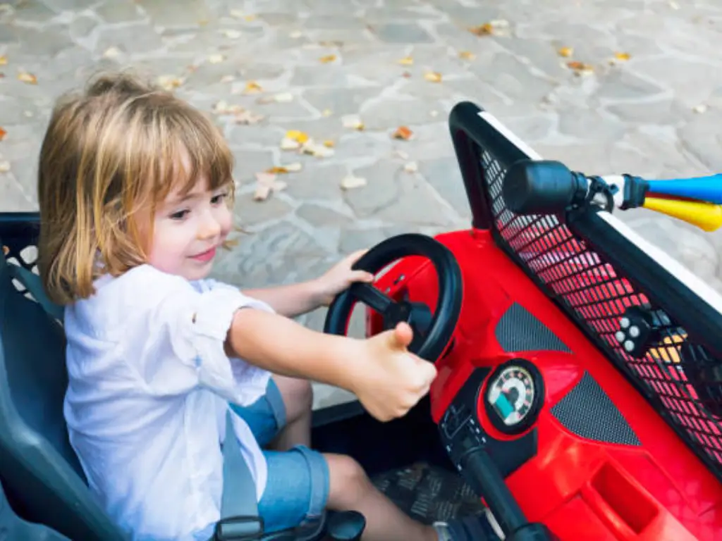 Une petite fille joue à la voiture