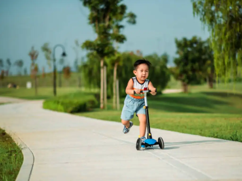 a little boy riding a scooter with joy