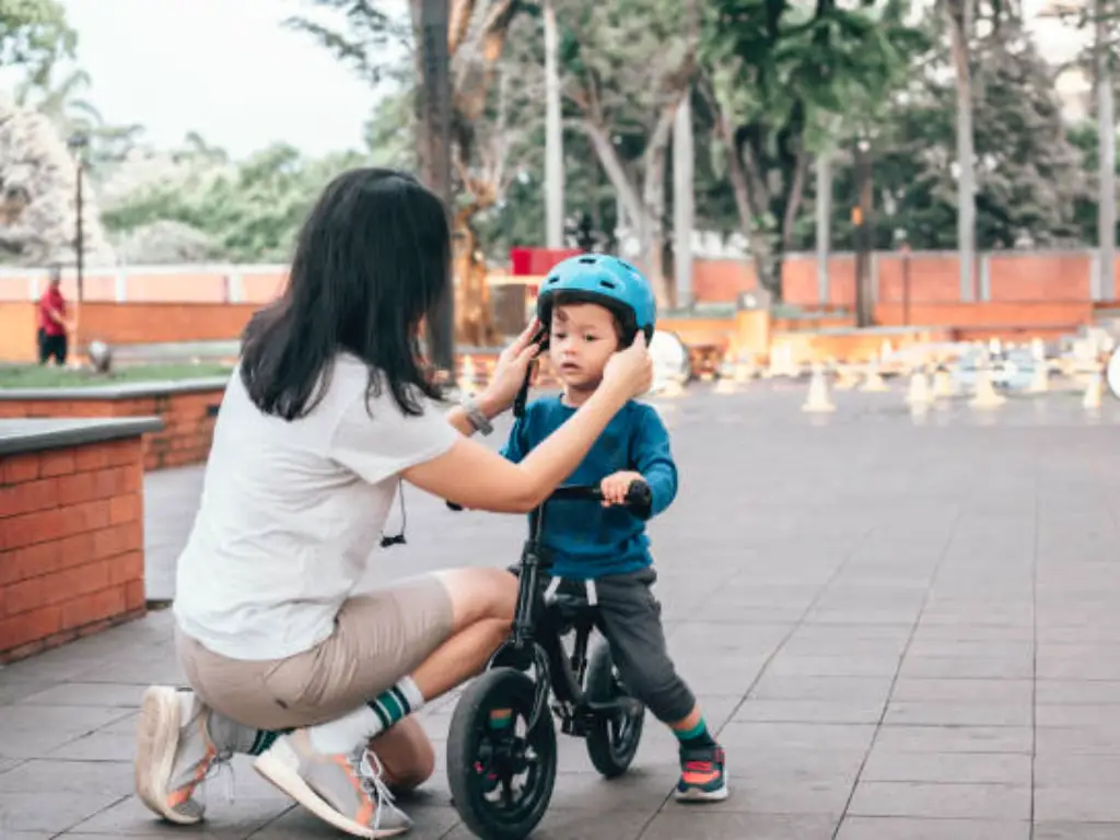 una madre ayuda a su hijo a llevar casco